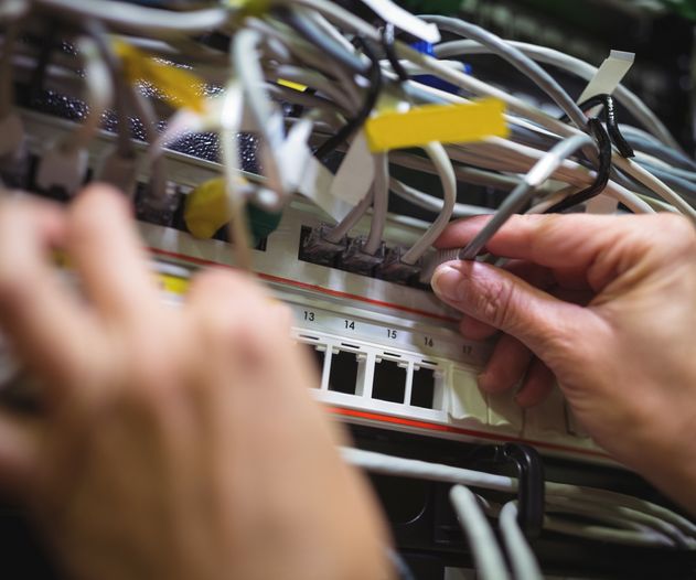 Technician plugging patch cable in a rack mounted server in server roo